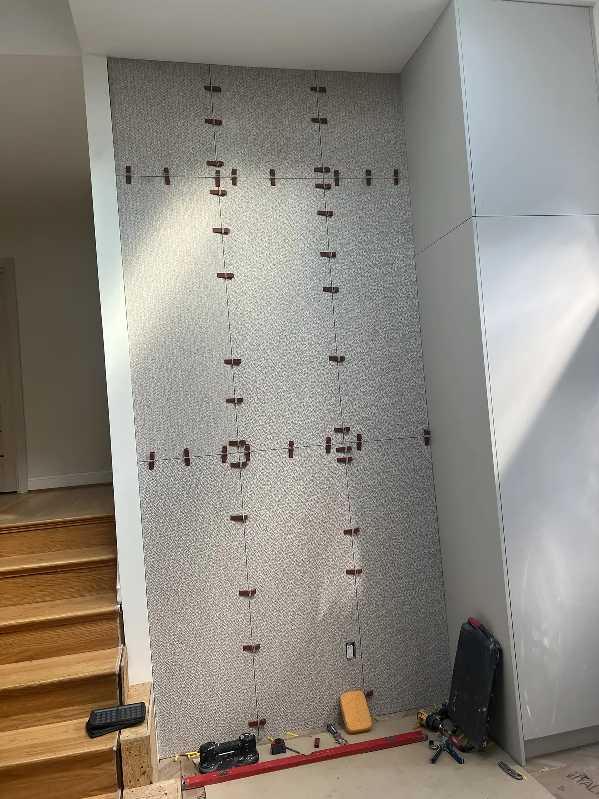 Textured large-format accent wall tile installation near stairs with clean vertical seams