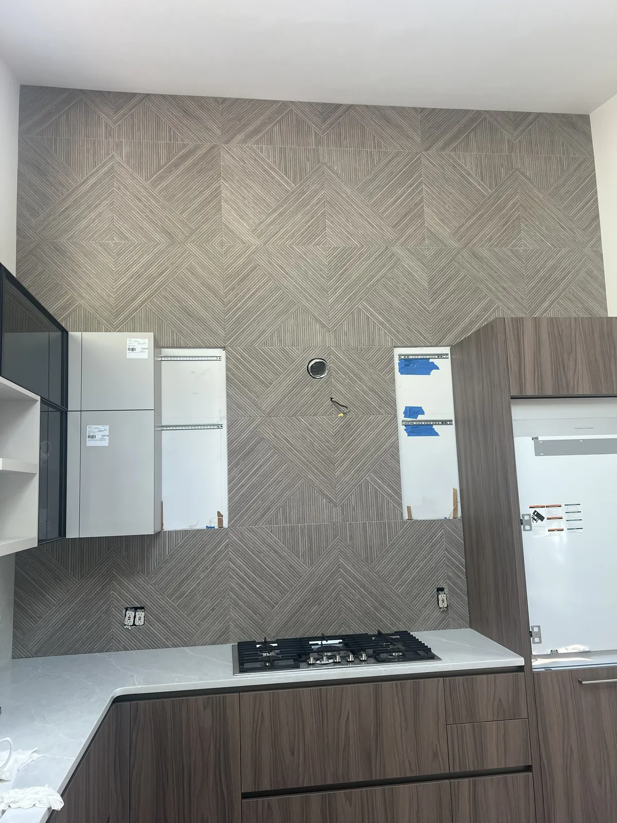 Tall kitchen range wall with textured geometric tile backsplash from counter to ceiling